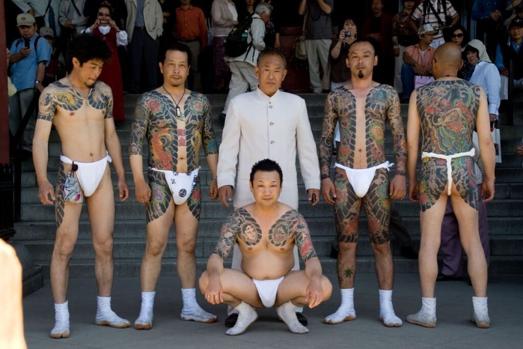 Five tattooed Japanese men pose around a sixth, well-dressed elder.